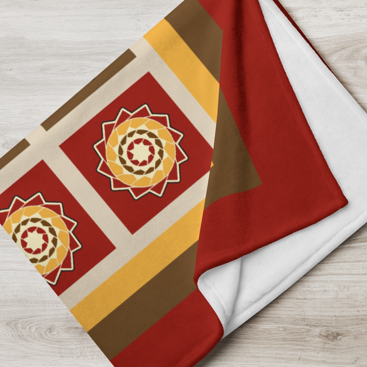 Printfull pinecone patchwork throw blanket in warm fall colors, displayed draped over a cozy living room setting.