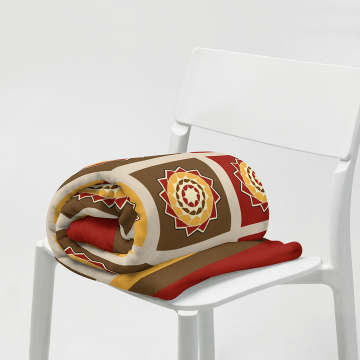 Printfull Pinecone Patchwork Throw Blanket in fall colors, displayed draped over a sofa for cozy home decor.